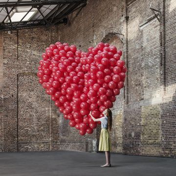 een vrouw met een groot hart gemaakt van honderden ballonnen