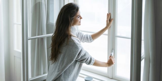 Woman in warm woolen pullover is opening window