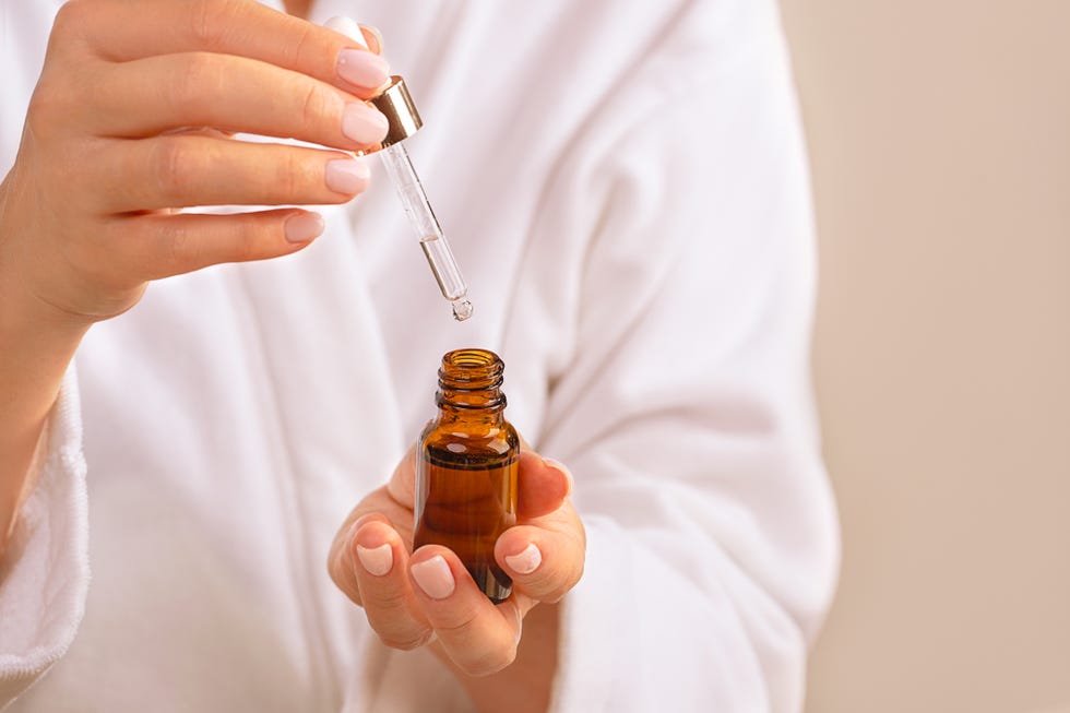 una mujer joven se va a aplicar un serum