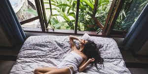 woman in white lingerie lounging in bed in the morning, view from window on tropical garden lifestyle photo