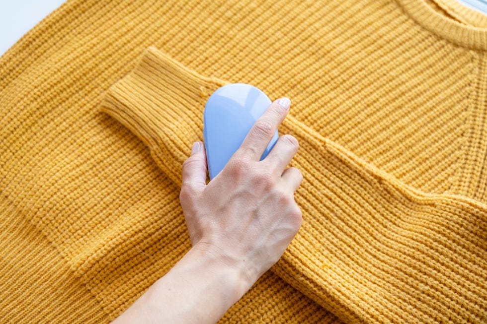 a fabric shaver removing pilling from a yellow jumper