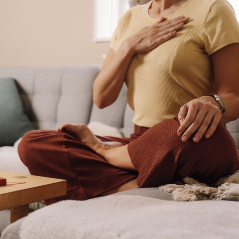 woman indoors relaxing meditating and doing breathing exercises