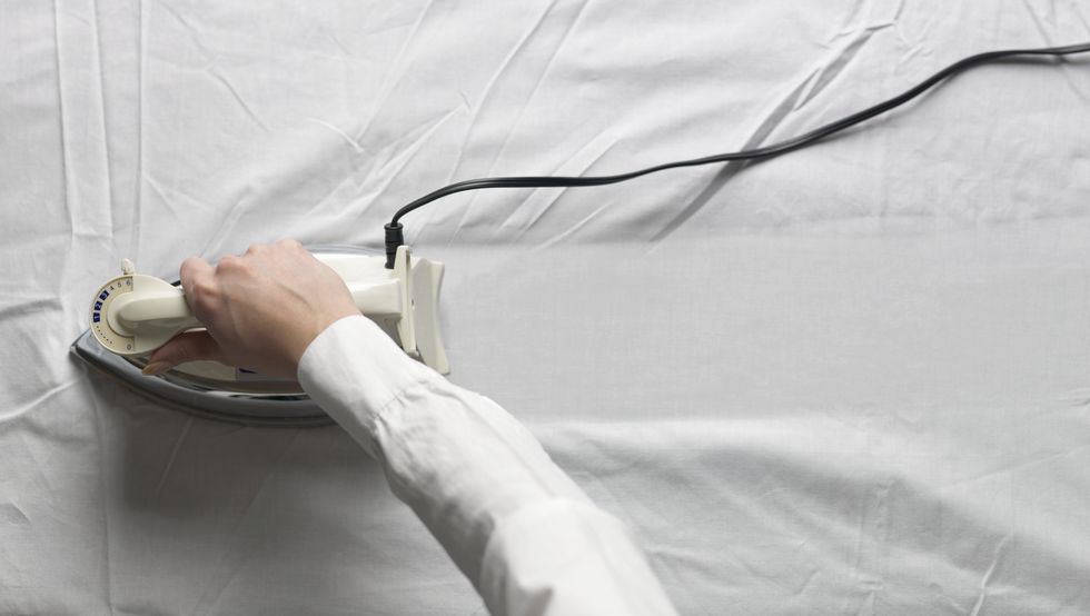 woman ironing white cloth, close up