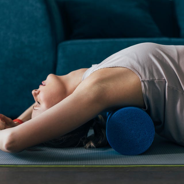 working out at home woman is sportswear using a roller to massage back muscles