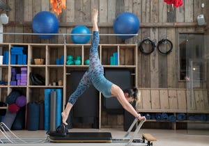 Woman is stretching on a reformer in pilates studio.