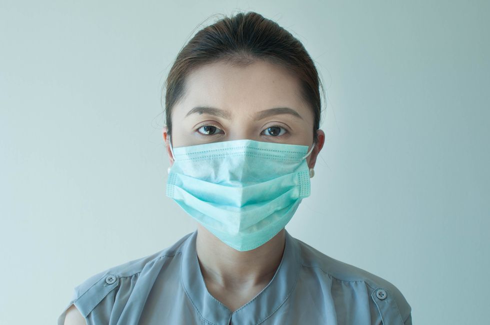 A woman is wearing a green surgical mask