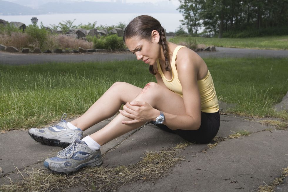 woman jogger holding injured knee