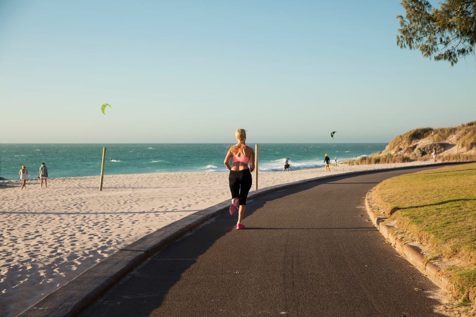 Woman jogging by the beach at sun set