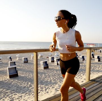 woman jogging on the beach boardwalk while listening to music on smartphone