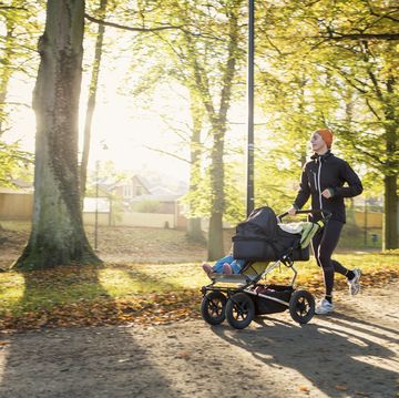 woman jogging with baby stroller on road at park