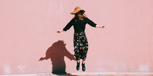 Woman Jumping Against Pink Wall