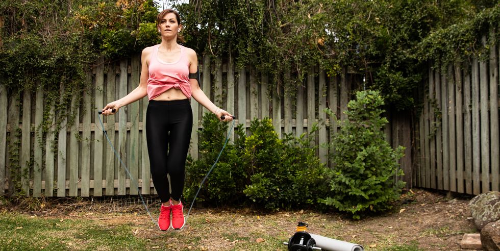 woman jumping with skipping rope in garden