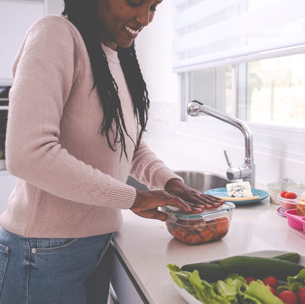 a woman packing up thanksgiving leftovers in a clear container