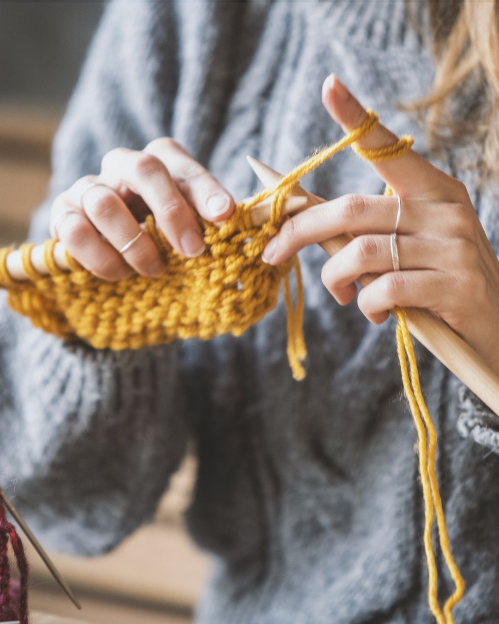 close up on womans hands knitting
