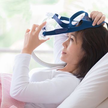 woman lay in bed wearing cpap mask ,sleep apnea therapy