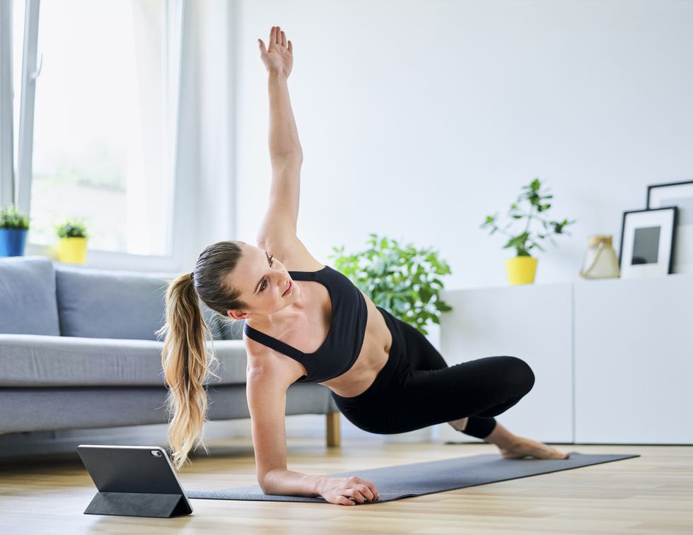 woman learning side plank exercise on internet through digital tablet