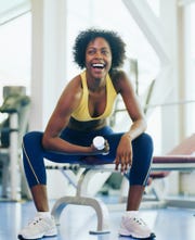 woman lifting dumbbell in gym, smiling, close up