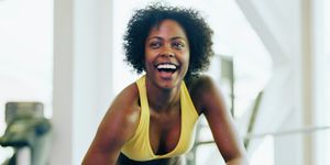 woman lifting dumbbell in gym, smiling, close up