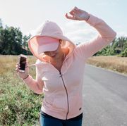 woman listening to music on her phone with headphones dancing outside