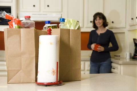 Food:  Woman looking at Grocery bags in the kitchen
