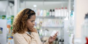 woman looking at label of medicine bottle at drugstore