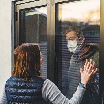 woman looking at masked husband quarantined behind window