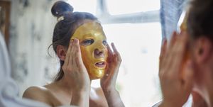 Woman looking in a mirror putting a face mask on