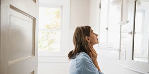 woman looking in bathroom mirror, touching neck