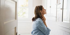 woman looking in bathroom mirror, touching neck