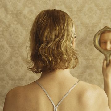 woman looking into hand mirror