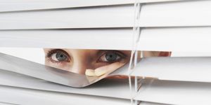 Woman looks through blinds