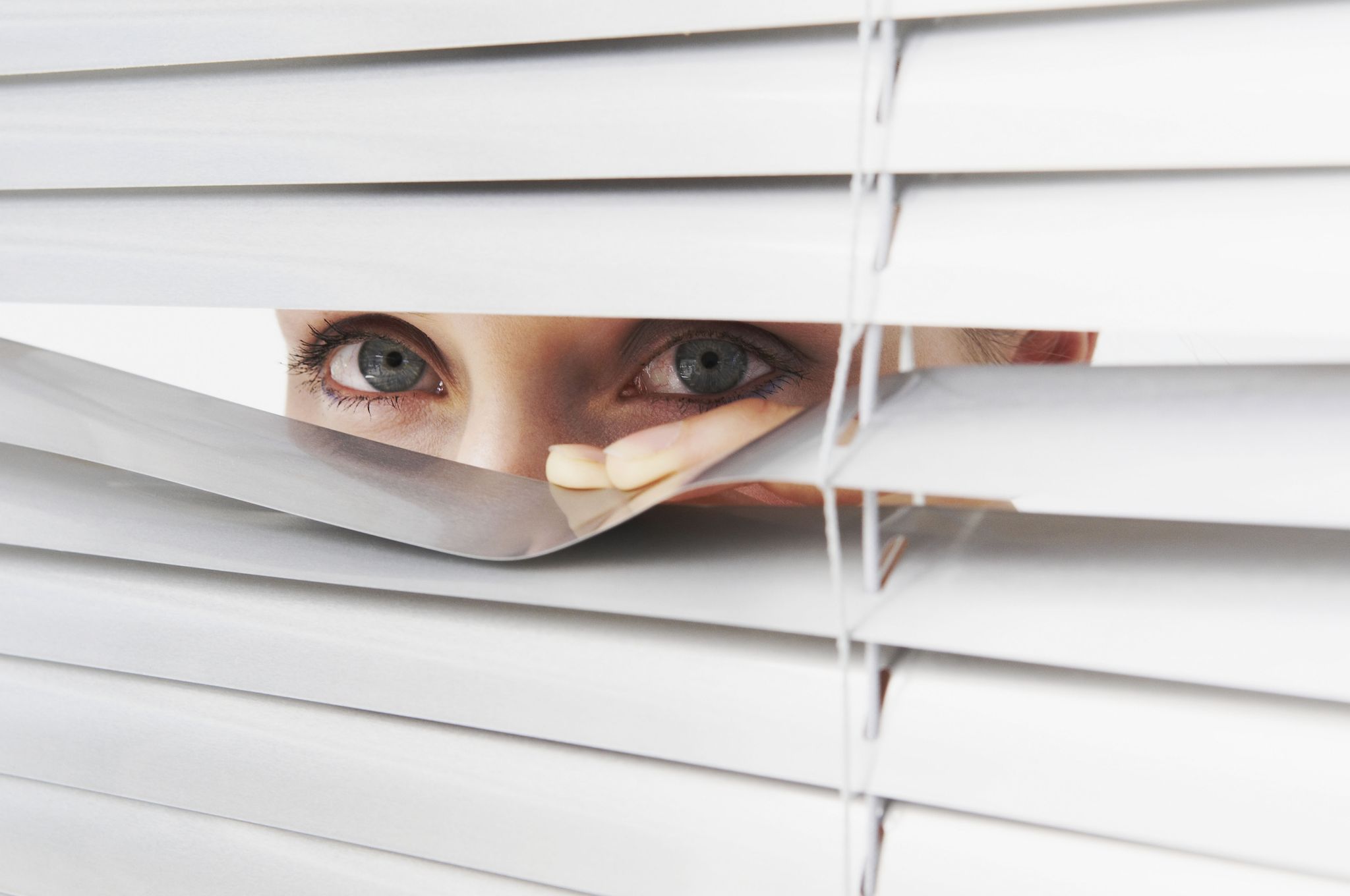Woman looks through blinds