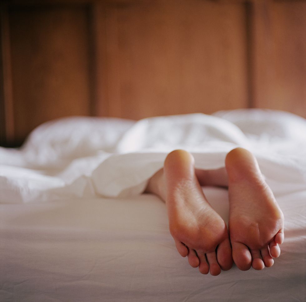 woman lying in bed under sheet