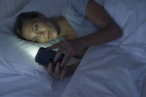 Woman lying in bed using smartphone