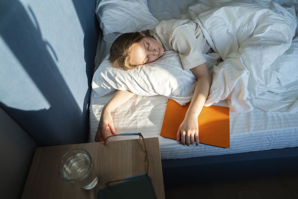 woman lying in bed with book at home