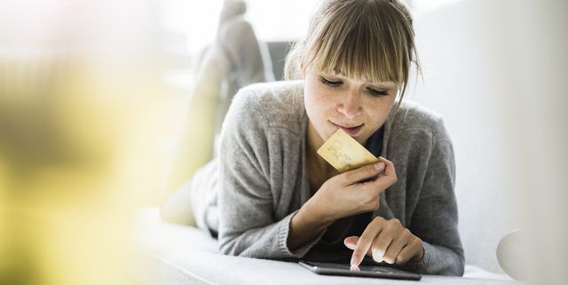 Woman lying on couch with credit card and tablet