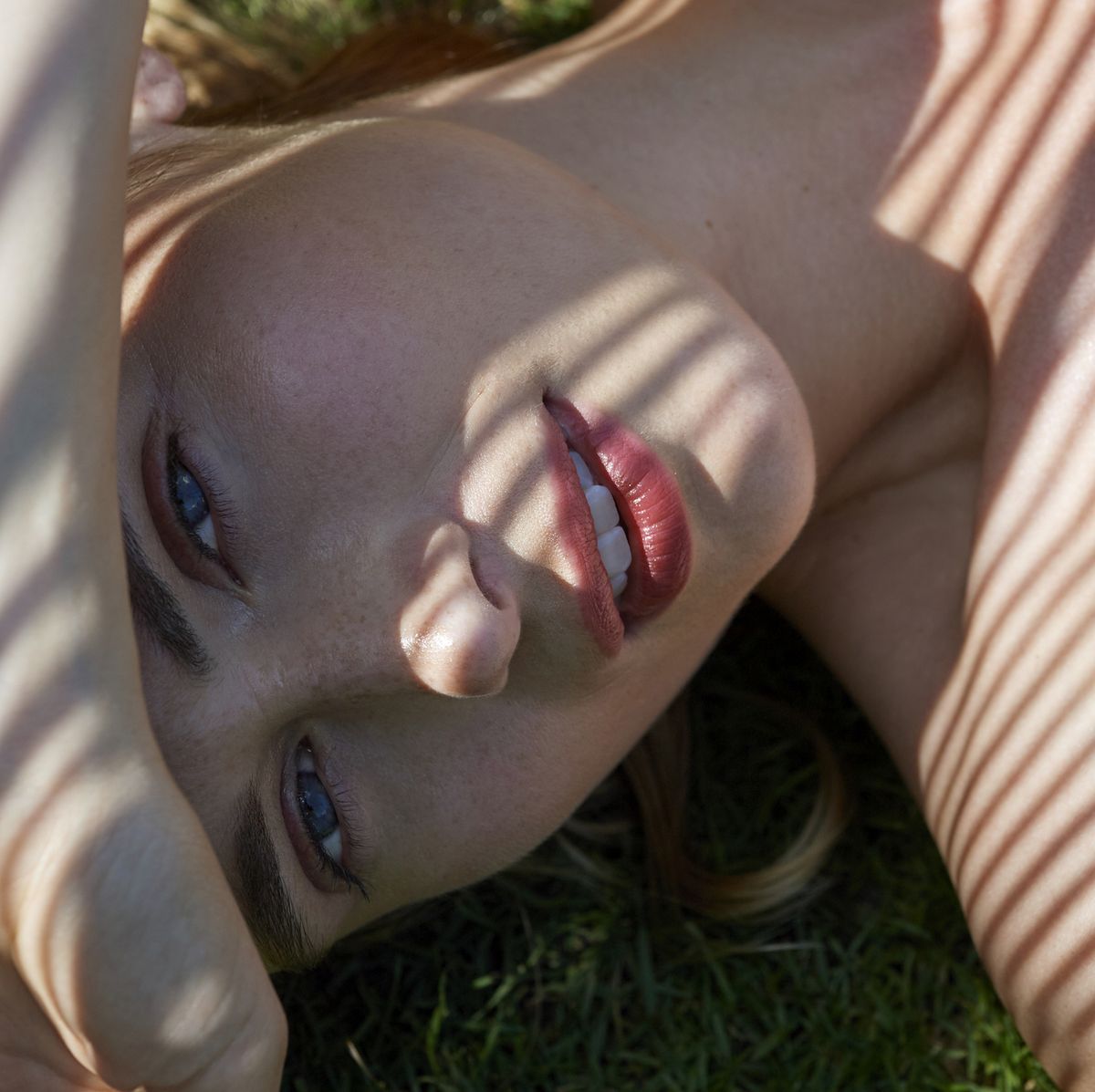 woman lying on grass with shadows cast on skin