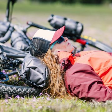 a woman lying on her mountain bike in a green meadow in spring