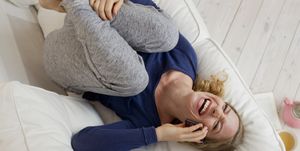 Woman lying on sofa laughing on smartphone
