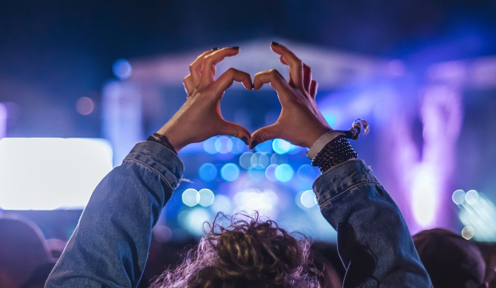 woman making heart shape with hands at music event