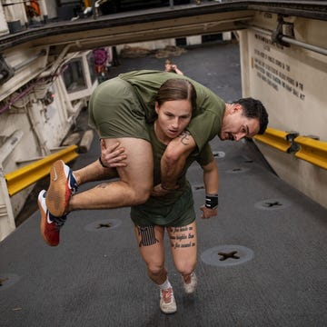 https://www.nationalgeographic.com/content/dam/magazine/rights-exempt/2019/11/military-women/woman-marine-body-carry.jpg Korporaal Gabrielle Green van het Amerikaanse marinierskorps USMC draagt een collega tijdens de voorbereiding op hun inzet op een marineschip in North Carolina Mariniers moeten elkaar kunnen tillen in noodsituaties Zon 3500 van de 38000 jaarlijkse USMCrekruten zijn vrouw