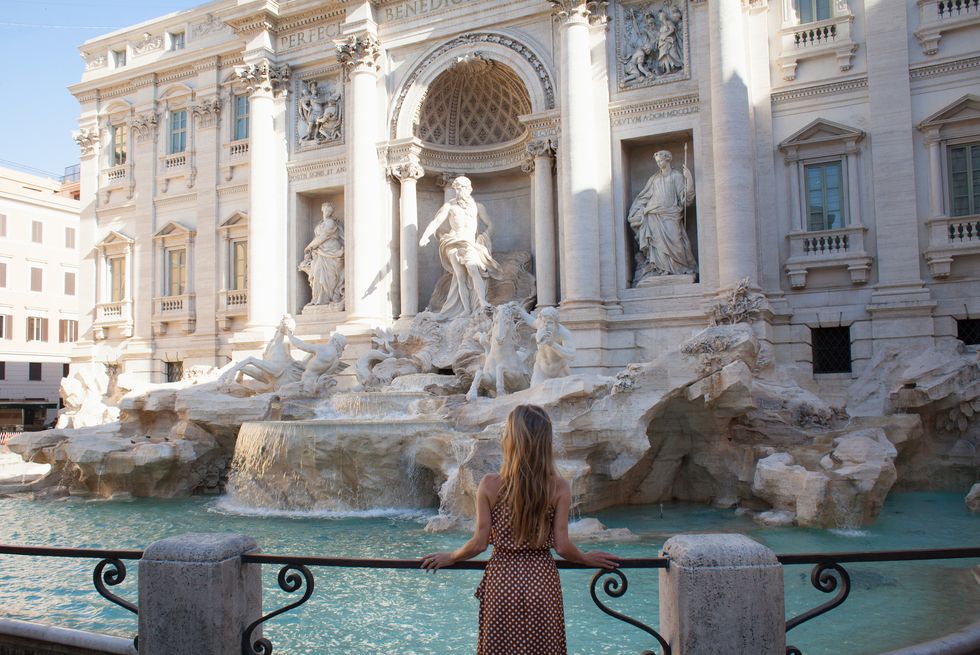 woman marvelling at trevi fountain in rome, italy