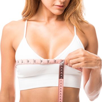 woman measuring her chest size over white background