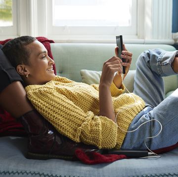 woman messaging on phone while leaning on friend