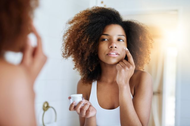 Woman using moisturizer in mirror