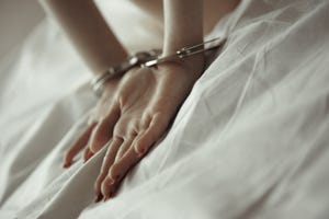 woman on the bed with hands in handcuffs