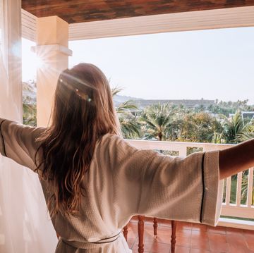 woman opening curtains in room at sunrise