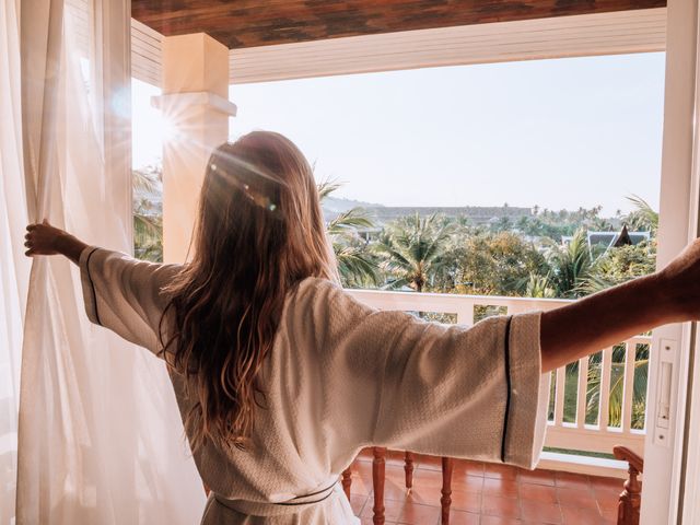woman opening curtains in room at sunrise
