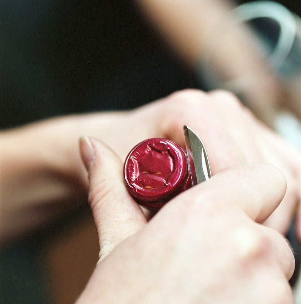 Woman opening red wine bottle