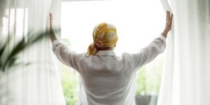 woman with cancer opening curtains